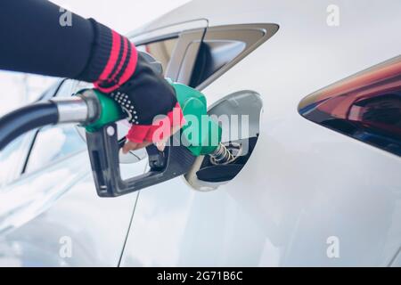 Fahrzeugbetankung an der Tankstelle. Weißes Auto an der Tankstelle, das mit Kraftstoff gefüllt wird. Das Fahrzeug an der Tankstelle von Hand mit Kraftstoff befüllen. T Stockfoto