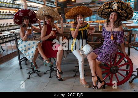 Eine Gruppe reifer Frauen trinkt in einem Pub Bier, das mexikanische Sombreros trägt Stockfoto