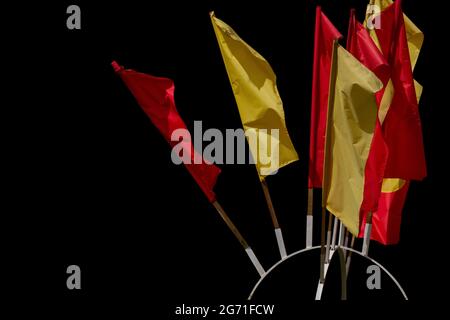 Textur aus mehrfarbigen festlichen roten, gelben Fahnen aus Stoff. Feiertagsfeier Satinfahnen in verschiedenen Farben im Wind. Isolieren Sie auf einem schwarzen Stockfoto