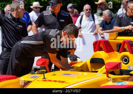 Ein Mann in Schwarz lehnt sich über einen gelb-roten Porsche RS Spyder Evo, bevor Romain Dumas beim Goodwood Festival of Speed 2021 die Bergauffahrt bestieg Stockfoto