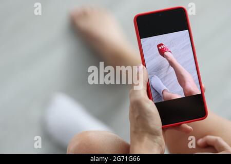 Frau versucht auf roten Sandalen mit Online-Umkleidezimmer-Konzept Stockfoto