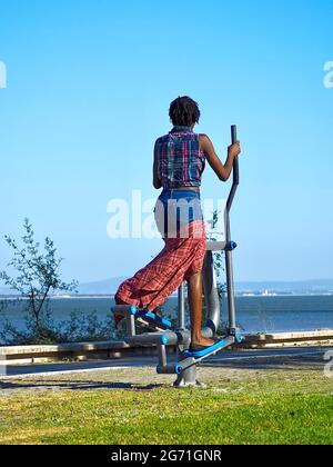 Schwarze Frau mit rotem Rock auf einem Stepper im Freien in Lissabon Stockfoto