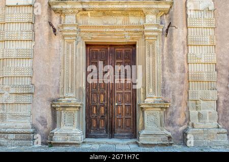 Kostbare Holztür an einer alten mittelalterlichen Kirchensteinmauer Stockfoto