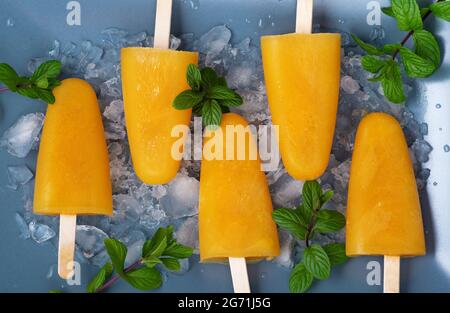 Leckere hausgemachte Popsicles mit Orangensaft Eisfrucht Lollies auf Sticks Ice Cube Top View Flat Lay. Orangeneis Stockfoto