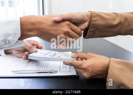 Ein männlicher Agent gab seinem gierigen Partner ein Bargeld, um dafür einen Gefallen zu bekommen. Stockfoto