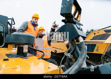 Zwei männliche Arbeiter auf Bagger im Grabenbetrieb oder Steinbruch auf Maschinen abgebildet Stockfoto