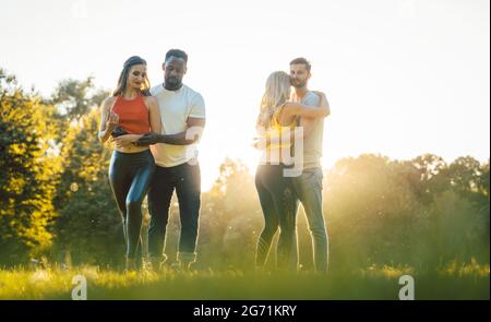 Zwei Paare tanzen fortgeschrittene Kizomba bewegt sich während Sonnenuntergang in einem Park Stockfoto