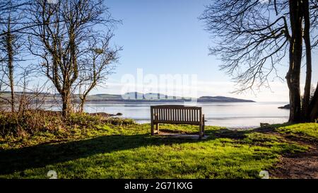 Holzbank mit Blick auf das Meer in Dhoon Bay an einem sonnigen Wintermorgen, Kirkcudbright, Schottland Stockfoto