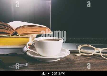 Tasse Kaffee und Laptop auf Holztisch