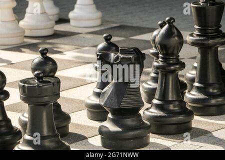 Schachbrett auf der Straße mit einer Sonne auf riesigen Schachfiguren Stockfoto