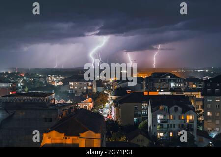 Gewitter und Gewitter in der Ferne hinter der Kleinstadt in der Nacht Stockfoto