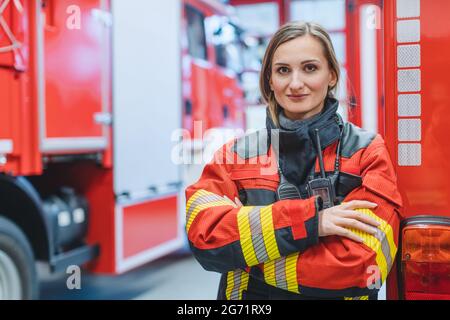 Feuerwehrfrau, die vor einem Feuerwehrauto steht Mit gekreuzten Armen Stockfoto