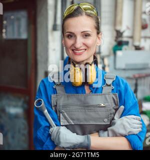 Eine Arbeiterin in ihrer Metallwerkstatt posiert mit Werkzeugen für die Kamera Stockfoto