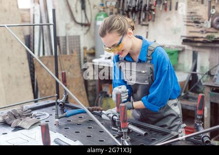 Frau in der Metallwerkstatt mit Werkzeugen und Werkstück hart arbeiten Stockfoto