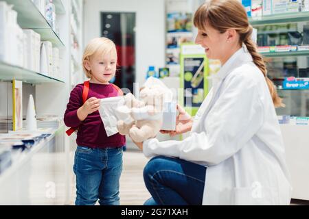 Apotheker Frau mit Kind Kunden und ihre Plüsch Spielzeug in der Pharmazie Stockfoto