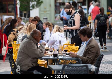 EMABRGOED TO 2230 SATURDAY JULY 10 Datei-Foto vom 29/06/21 einer Kellnerin mit Gesichtsbedeckung, die Gäste an Tischen im Freien in Kensington, London, serviert. Im Mittelpunkt des Plans von Premierminister Boris Johnson, das Land aufzupolieren, stehen Take-away-Pints und Speisen im Freien, die er nächste Woche in einer Rede verraten wird. Johnson wird unter dem Dach der Nivellierung, die bei den Parlamentswahlen 2019 als ein Antrieb zur Behebung regionaler Ungleichheiten im Vereinigten Königreich angepriesen wurde, eine neue Strategie zur Wiederbelebung der hohen Straßen in Gang setzen. Ausgabedatum: Samstag, 10. Juli 2021. Stockfoto