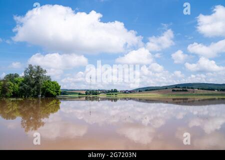 Gleusdorf, Deutschland. Juli 2021. Die Landschaft spiegelt sich in der Wasseroberfläche eines überfluteten Feldes wider. Teile von Franken sind aufgrund des hohen Wassers von gestern noch unter Wasser. Quelle: Nicolas Armer/dpa/Alamy Live News Stockfoto