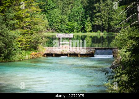 Kleiner Damm über einem Fluss, umgeben von Grün unter dem Sonnenlicht Stockfoto