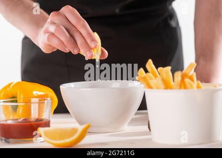 Zitronensaft mit der Hand in eine Schüssel mit Zutaten pressen Stockfoto