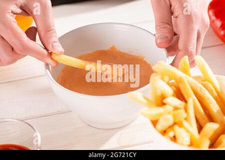 Aus der Nähe auf einer Hand tauchen Pommes in Sauce andalouse. Stockfoto