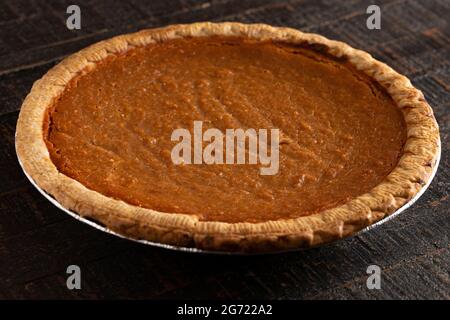 Eine ganze Süßkartoffel-Torte auf einem Tisch aus dunklem Holz Stockfoto