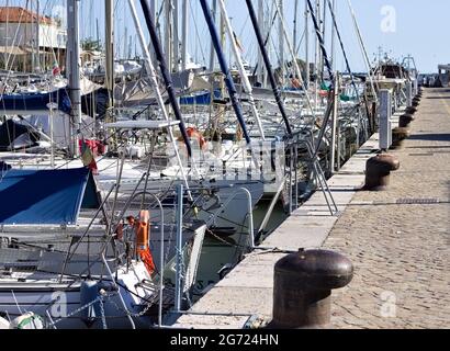 Eine Reihe von Booten, die im Hafen von Pesaro vor den Ankerbooten auf dem Pier (Marken, Italien, Europa) festgemacht sind Stockfoto