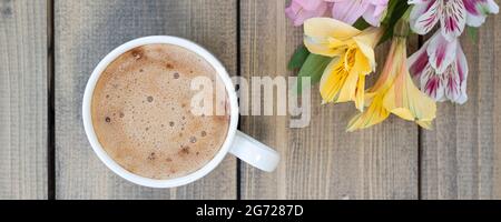 Banner mit flacher Lay mit bunten Blumen und Tasse Kaffee. Bunte Alstroemerien, rosa, gelb, lila und rot Alstroemerien in der Nähe einer Tasse. Konzept Glückwünsche oder Urlaub. Weichfokus Stockfoto