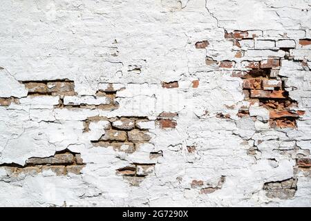 Verwitterte Ziegelwand mit zerbröckelndem weißen Gips für den Hintergrund Stockfoto