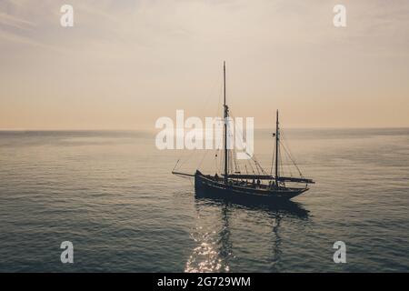 AT SEA, CORNWALL, GROSSBRITANNIEN - 30. JUNI 2021. Ein wunderschönes, hohes Schiff, das bei Sonnenuntergang auf einem ruhigen Meer schwimmt und Platz für Kopien bietet Stockfoto