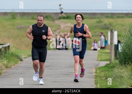 Shoeburyness, Essex, Großbritannien. Juli 2021. Aufgrund der COVID-19-Pandemie wurde der Triathlon 2020 verschoben, um wieder zurückzukehren, da die Beschränkungen für 2021 aufgehoben werden. Die Wettkämpfer, die im Shoeburyness-Gebiet östlich von Southend on Sea stattfinden, begannen den Wettbewerb mit einem 750-Meter-Schwimmen in der Themse-Mündung, bevor sie mit ihren Fahrrädern eine 20km-Fahrt durch Landstraßen und einen 5km-Lauf im Gunners Park an der Küste zurücknahmen Seine imposanten Verteidigungsstrukturen im Krieg. Das ehemalige Mod-Gebiet ist heute ein Naturschutzgebiet und beliebtes Wandergebiet Stockfoto