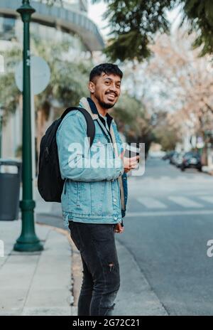 Der junge argentinische, stilvolle bärtige, fröhliche Mann posiert mit einer Tasse Kaffee auf der Straße Stockfoto