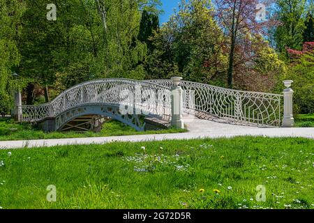 Brücke. Dekorative weiße Metallbrücke über den Bach im Park, Erholungsgebiet. Das Ende des Sommers, der Anfang des Herbstes. Es gibt eine Wanderpr Stockfoto