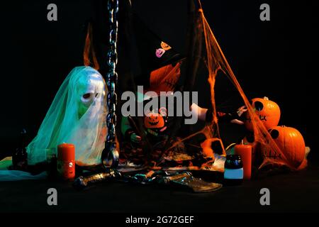 Lustiges Kindermädchen im Hexenkostüm für Halloween mit Kürbis Jack und orangefarbenem Ballon auf dunklem Holzhintergrund