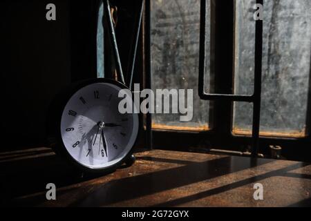 EIN WECKER AUF DEM TISCH NEBEN DEM FENSTER Stockfoto