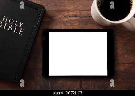 Bibel und Kaffee mit einer weißen Tafel auf einem Holztisch, um Ihren Text hinzuzufügen Stockfoto