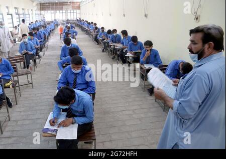 Matrizenstudenten lösen während der jährlichen Matrikulationsprüfung 2021 in Peshawar am Samstag, den 10. Juli 2021, in einem Prüfungszentrum mit SOPs-Stufen zu den staatlichen Richtlinien für Gesichtsmaske und soziale Distanzierung als Präventivmaßnahme gegen die Ausbreitung des Coronavirus (COVID-19). Stockfoto