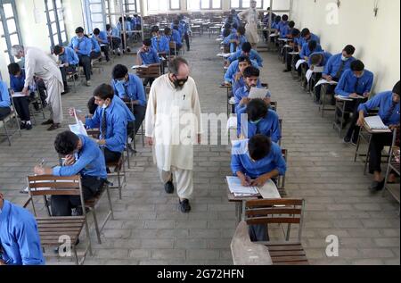 Matrizenstudenten lösen während der jährlichen Matrikulationsprüfung 2021 in Peshawar am Samstag, den 10. Juli 2021, in einem Prüfungszentrum mit SOPs-Stufen zu den staatlichen Richtlinien für Gesichtsmaske und soziale Distanzierung als Präventivmaßnahme gegen die Ausbreitung des Coronavirus (COVID-19). Stockfoto