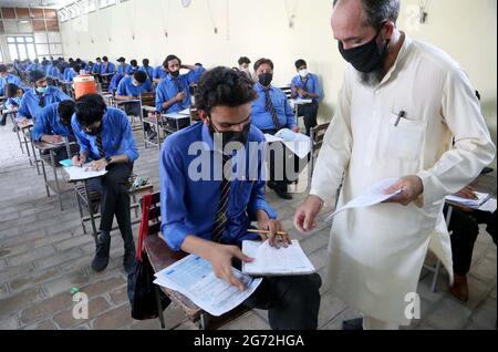 Matrizenstudenten lösen während der jährlichen Matrikulationsprüfung 2021 in Peshawar am Samstag, den 10. Juli 2021, in einem Prüfungszentrum mit SOPs-Stufen zu den staatlichen Richtlinien für Gesichtsmaske und soziale Distanzierung als Präventivmaßnahme gegen die Ausbreitung des Coronavirus (COVID-19). Stockfoto