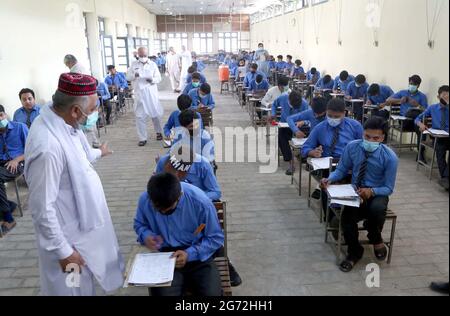 Matrizenstudenten lösen während der jährlichen Matrikulationsprüfung 2021 in Peshawar am Samstag, den 10. Juli 2021, in einem Prüfungszentrum mit SOPs-Stufen zu den staatlichen Richtlinien für Gesichtsmaske und soziale Distanzierung als Präventivmaßnahme gegen die Ausbreitung des Coronavirus (COVID-19). Stockfoto