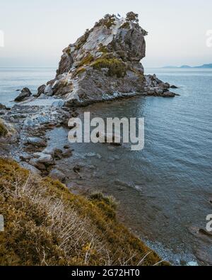 Vertikale Ansicht der Kirche von Agios Ioannis Kastri auf der griechischen Insel Skopelos bei Sonnenuntergang. Die Kirche, die sich auf der Spitze der Klippe befindet, ist berühmt für Stockfoto