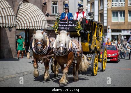 Nürnberg, Deutschland. Juli 2021. Die historische Museumskutsche aus dem Nürnberger Museum für Kommunikation fährt in einer Parade der Nürnberger Museen durch die Innenstadt. Mit Musik, Künstlern und Exponaten bewarben sich 23 Nürnberger Museen auf einer Parade durch die Innenstadt. Die Parade wurde von staatlichen und privaten Museen sowie von drei Museen, die gerade gegründet wurden, organisiert. Es war der Auftakt zur Veranstaltungsreihe "Muse im Museum", in der die Nürnberger Museen kreative Künstler in ihre Räume einladen. Quelle: Daniel Karmann/dpa/Alamy Live News Stockfoto