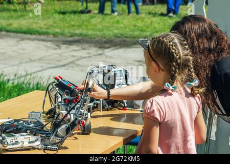 Zaporizhia, Ukraine- 19. Juni 2021: Charity Family Festival: Mädchen und ihre Mutter erkunden Roboter auf der Outdoor Modern Technologies Ausstellung. Stockfoto