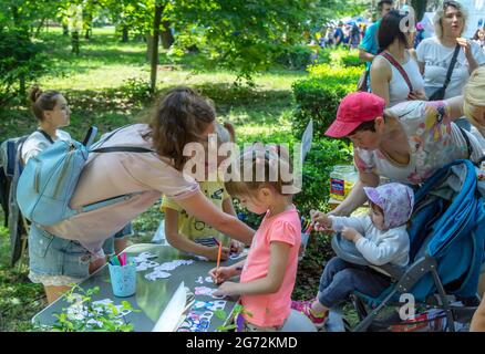 Zaporizhia, Ukraine- 19. Juni 2021: Charity Familienfest: Kinder malen lustige Papierfiguren, die an einem Kunst- und Bastelworkshop im Freien teilnehmen Stockfoto
