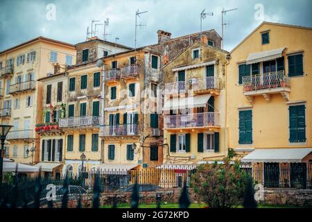 Korfu-Insel/Griechenland - 4. Mai 2019: Blick auf alte und verwitterte Gebäudefassaden - Wand mit geschälter Farbe, grüne Holzläden an den Fenstern. Kerkyra o Stockfoto