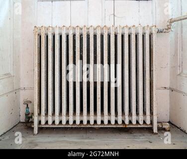 Alter, gusseiserner Heizkörper in verwahrlossenem Haus. Stockfoto