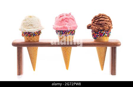 Schaufeln Sie klassische Vanille Erdbeere und Schokolade Eis Aromen in Zuckerzapfen Stockfoto