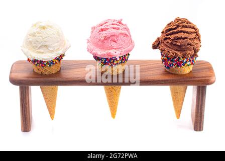 Schaufeln Sie klassische Vanille Erdbeere und Schokolade Eis Aromen in Zuckerzapfen Stockfoto