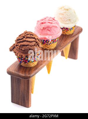 Schaufeln Sie klassische Vanille Erdbeere und Schokolade Eis Aromen in Zuckerzapfen Stockfoto