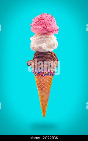 Eiskegel mit Erdbeer-Vanille und Schokolade in einem spitzen Zuckerkegel, der in der Luft schwimmt Stockfoto