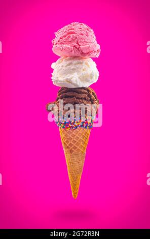 Eiskegel mit Erdbeer-Vanille und Schokolade in einem spitzen Zuckerkegel, der in der Luft schwimmt Stockfoto